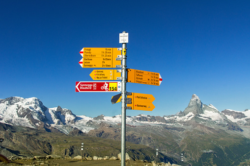 Signpost written in German of various hiking trails in Swiss Alps mountains, Zermatt, Switzerland