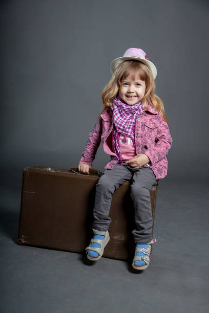 istock Little girl in hat sits on large suitcase bag. 1222913974