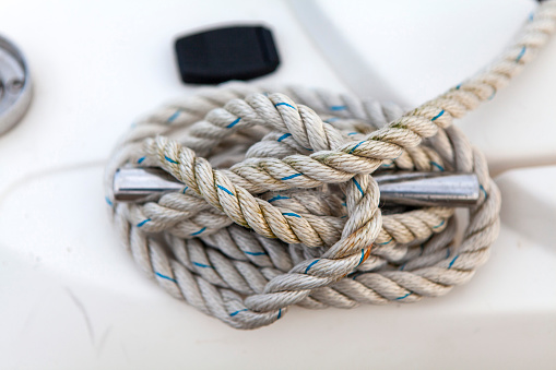 White mooring rope wound round a cleat on the side of a boat