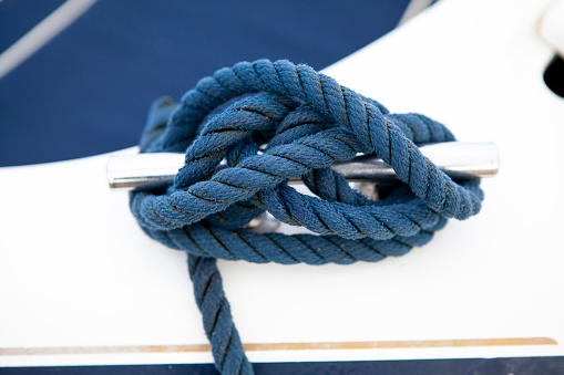 Blue mooring rope wound round a cleat on the side of a boat