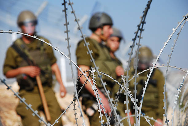 Razor Wire and Soldiers Four Israeli soldiers stand behind razor wire near the Palestinian village of Bil'in in the West Bank israel stock pictures, royalty-free photos & images