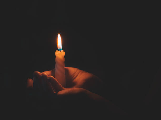 istock Burning candle in male hand on a black background 1222926091