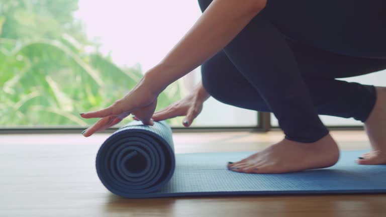 Woman rolling out yoga mat and preparing to meditate training in yoga