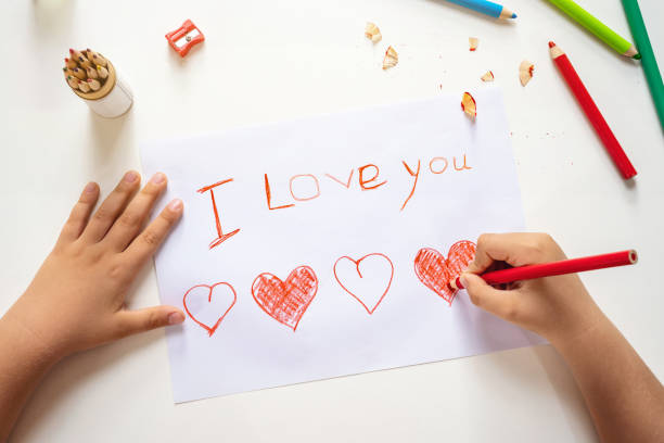 High angle view of child drawing I love you sign High angle view of childs hands drawing I love you sign on the paper sheet i love you photos stock pictures, royalty-free photos & images