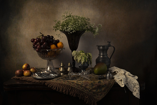 Objects on the table is an ancient vase of flowers, fruit, wine glass.The photo was taken using a light effect brush.