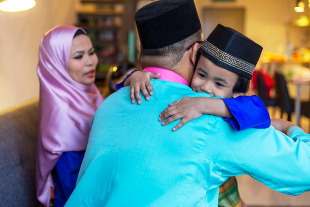 Father and young son hugging each other during islamic festive celebration Asian Muslim father hugging his son during traditional Hari Raya Puasa celebration hari raya family stock pictures, royalty-free photos & images