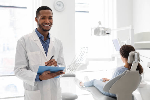 istock Black dentist smiling and holding folder in dental cabinet 1222938825