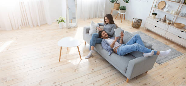 joven familia de dos relajarse en el sofá en casa - internet lifestyles wireless technology relaxation fotografías e imágenes de stock