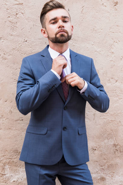 istock Young man in a gray business suit posing on concrete wall background 1222940914