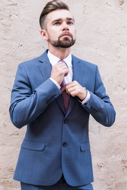 istock Young man in a gray business suit posing on concrete wall background 1222940972
