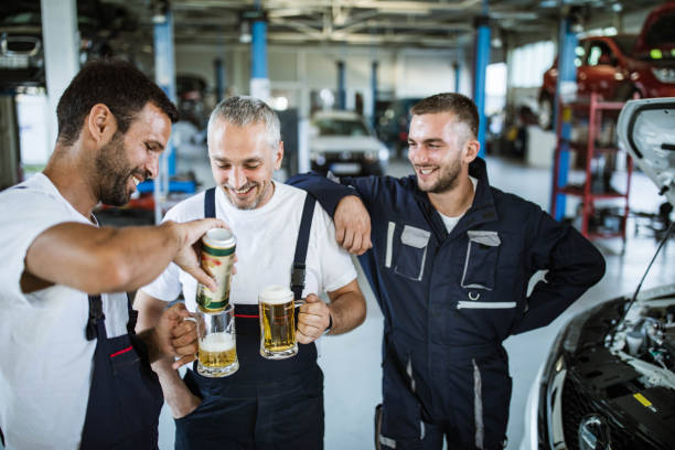 Happy auto mechanics drinking beer on a break in a workshop.
