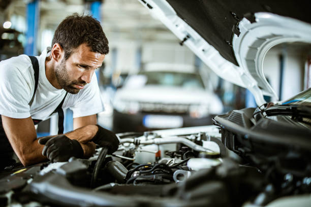 istock Worried mechanic examining engine problems in auto repair shop. 1222944400