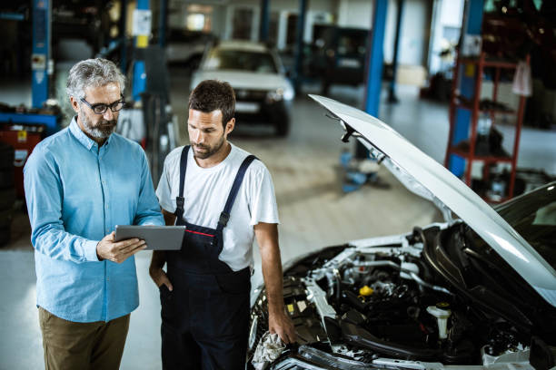 istock Mid adult inspector and auto repairman using touchpad in a workshop. 1222944480
