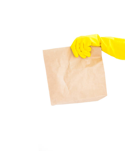 nahaufnahme hand in gelben handschuh halten braun klar leere leere handwerk papiertasche zum mitnehmen isoliert auf weißem hintergrund. - supermarket fast food fast food restaurant people stock-fotos und bilder