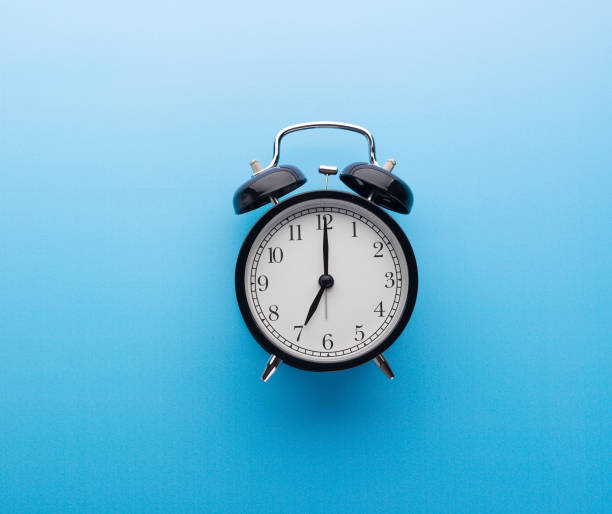 istock Black Vintage Alarm Clock on Blue Background Isolated Ticking Seven O Clock 1222945900