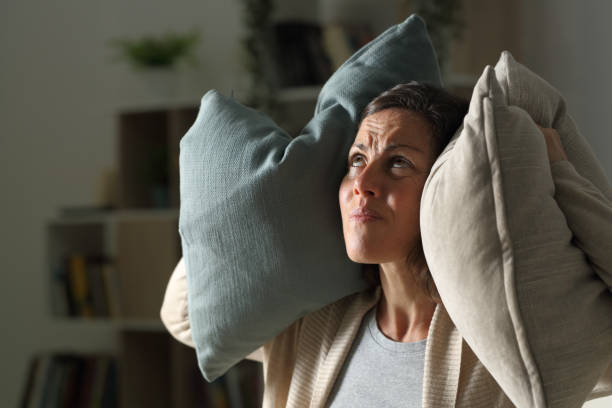 femme adulte ennuyé souffrant le bruit de voisin la nuit à la maison - irritants photos et images de collection