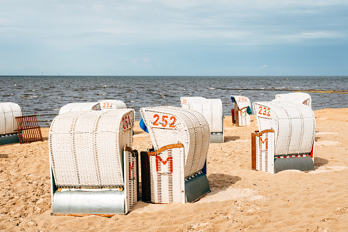 Sandy beach and typical hooded beach chairs in Cuxhaven in the North Sea coast a cloudy day of Summer. Germany