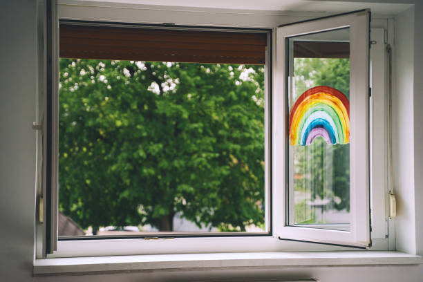 istock Open window in room with green trees on background. Painting rainbow on window. 1222947793