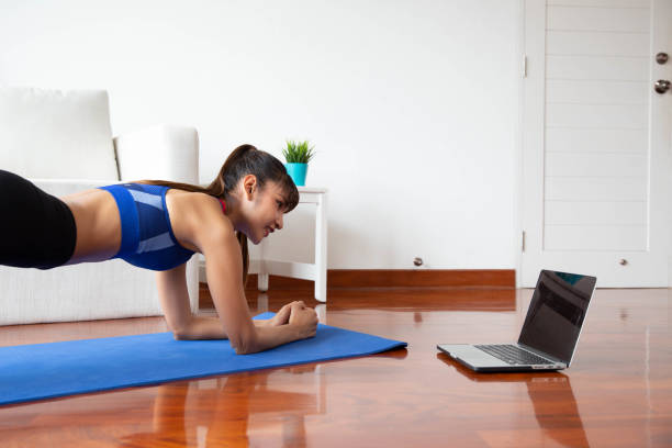 istock Young asian woman exercising at home in a living room with computer notebook 1222949116