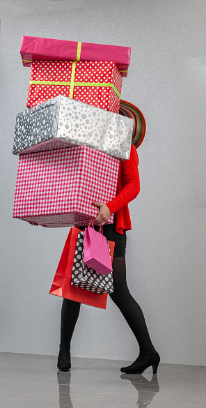 Woman with straw hat balancing gifts purchased for holidays, birthday, or during shopping spree