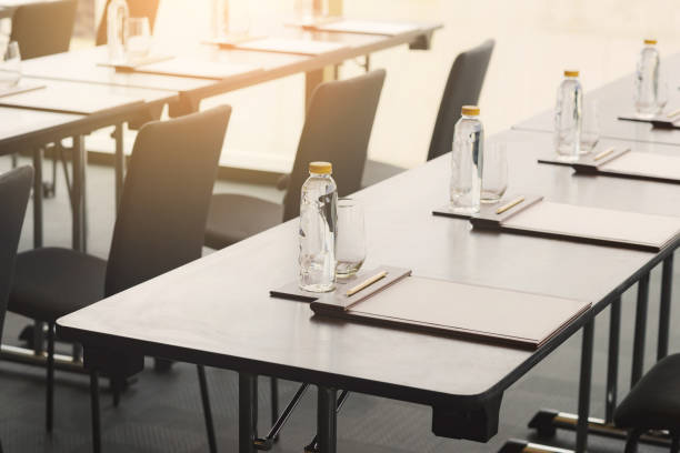 istock Plastic water bottles, Drinking glasses with pencil and white papers setup on the table prepared for seminar or business meeting in the hotel conference room 1222949454