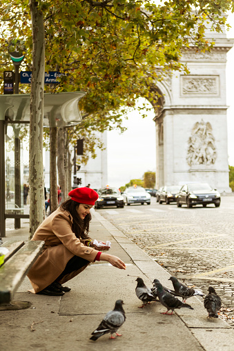 asian traveler feeding pigeon birds on the street in Paris City, France