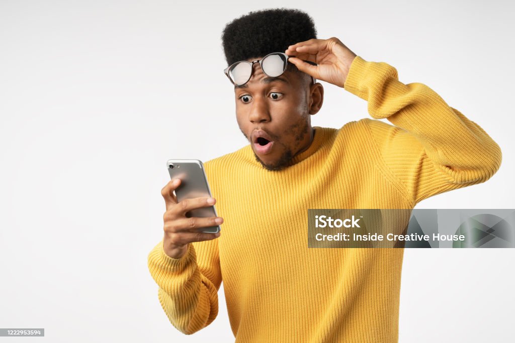 Shocked african man while watching in smartphone on isolated white background Background, African Ethnicity, People, Males, Copy Space People Stock Photo