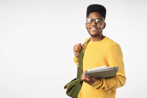 studente universitario felice in occhiali con zaino che tiene il laptop isolato su sfondo bianco - afro americano immagine foto e immagini stock