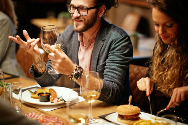 istock Hipster sitting with his friends at restaurant for diner, drinking wine and chatting. 1222955002