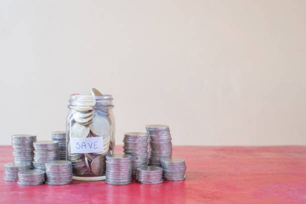 istock Saving coins in glass with stack of coins on red wooden table. Workplace with copy space - Investment, Business, Finance and Banking Concept 1222956853