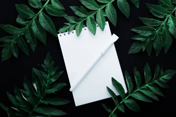 istock Spiral notepad mockup with frame made of green tropical leaves 1222964088