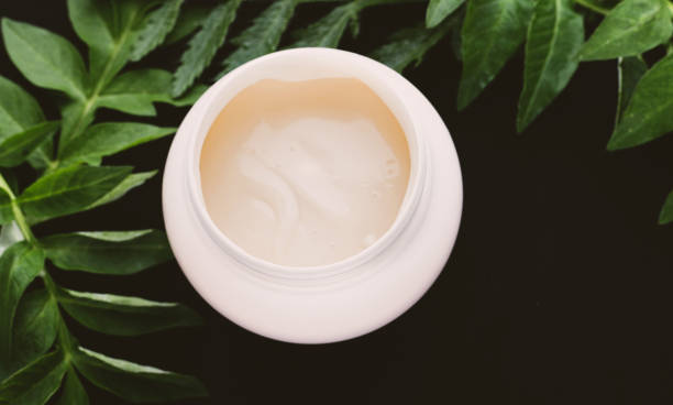 istock spa cream and green leaves on dark background 1222964090
