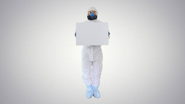 istock Lab scientist in safety suit holding empty white board on gradient background 1222965553