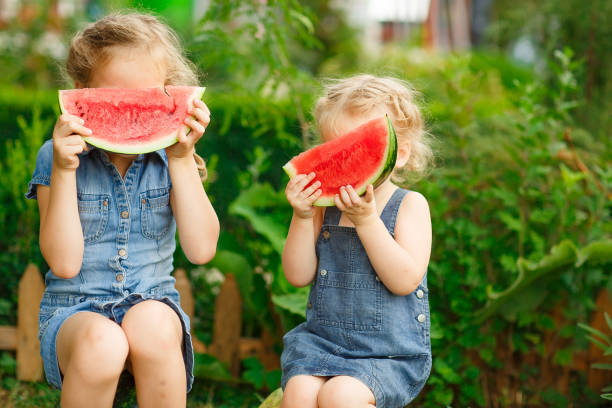 istock Little girls sit on watermelon and keep pieces 1222967587
