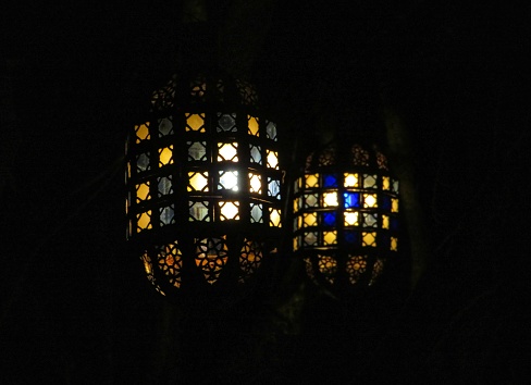 A pair of old fashioned looking lanterns shine a light in the dark.