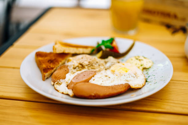 istock Helpful appetizing breakfast on a white plate. Scrambled eggs with vegetables and croutons in a cafe. Breakfast in the cafe: scrambled eggs, sausages and toast. 1222969854