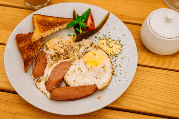 istock Fried eggs with tomatoes, cucumbers and cheese for breakfast. Scrambled eggs with sausages and tomatoes in a cafe. Comprehensive breakfast with eggs, ham, vegetables and toast. 1222969899