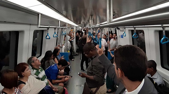 View Of People Sitting Down, Standing, Reading Text Message With Smartphone, Looking Around, Talking To One Another Inside Metro In Rio De Janeiro Brazil