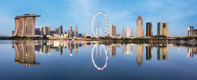 Singapore, Republic of Singapore - October 12, 2019: Supertree grove, Cloud garden greenhouse and Marina Bay Sands hotel reflecting in water at dusk with glowing lights