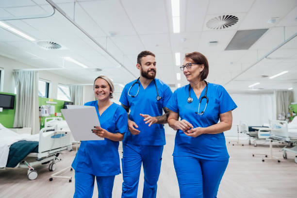 I Love My Coworkers A shot of three healthcare workers walking and talking through the hospital ward. medical student photos stock pictures, royalty-free photos & images