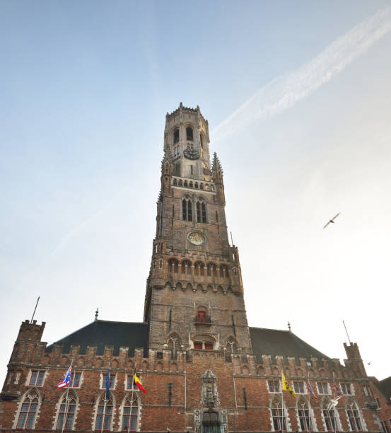 vista ad angolo basso di un campanile medievale (belfry of bruges) in un centro storico della città al tramonto. cielo azzurro chiaro con nuvole di cirrus. guida di viaggio, tema turistico. belgio - international landmark bruges belgium clear sky foto e immagini stock