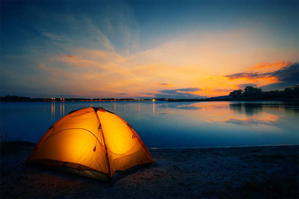 tente orange sur le lac au crépuscule - sunset vacations orange glowing photos et images de collection