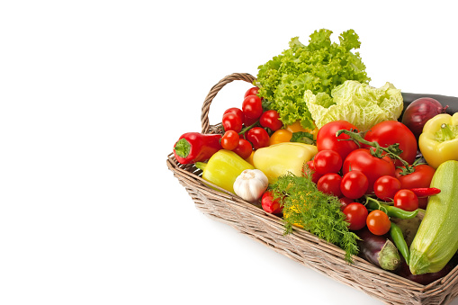 Fresh and ripe vegetables arranged in a basket isolated on white. Healthy vegan food. Photo with free space for text.