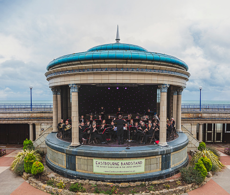 Eastbourne, Sussex, UK - September 22, 2019: Famous art deco bandstand in Eastbourne, Sussex. The orchestra is playing; people are sitting and watching the concert.