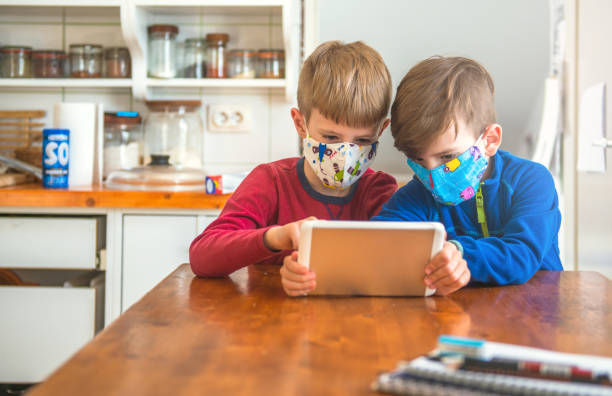 istock Boys Playing With Digital Tablet And Wearing Protective Face Mask 1222978122