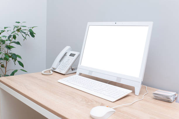 istock Isolated white computer display for mockup on desk in bright cozy office with white computer mouse and telephone 1222981101
