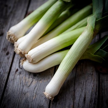 Close up of fresh leek on dark, wooden background.