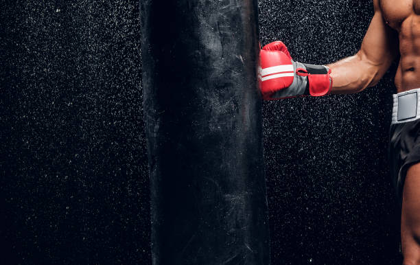 istock Strong arm of powerful fighter and punching bag 1222998624