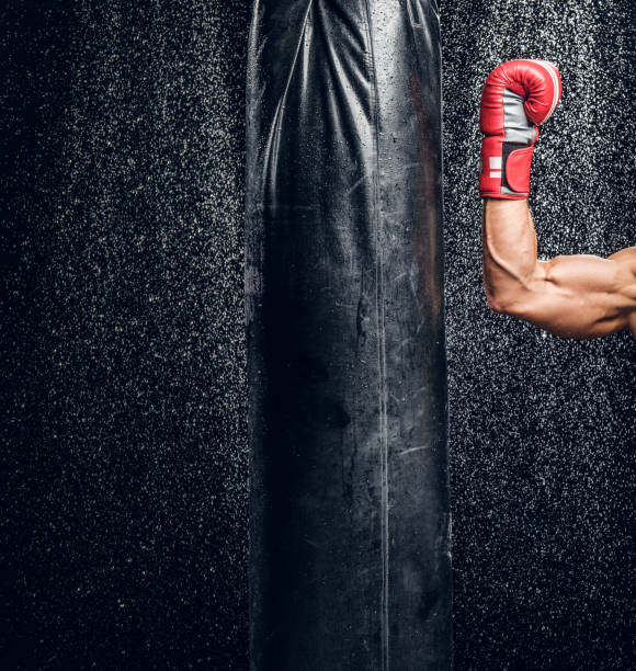 istock Strong arm of powerful fighter and punching bag 1222998640