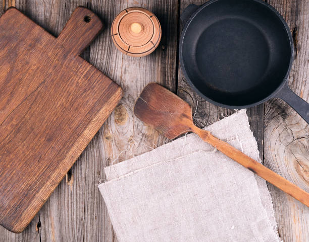 istock empty black round cast iron pan with handle, wooden cutting board and knife on a gray table 1222999693
